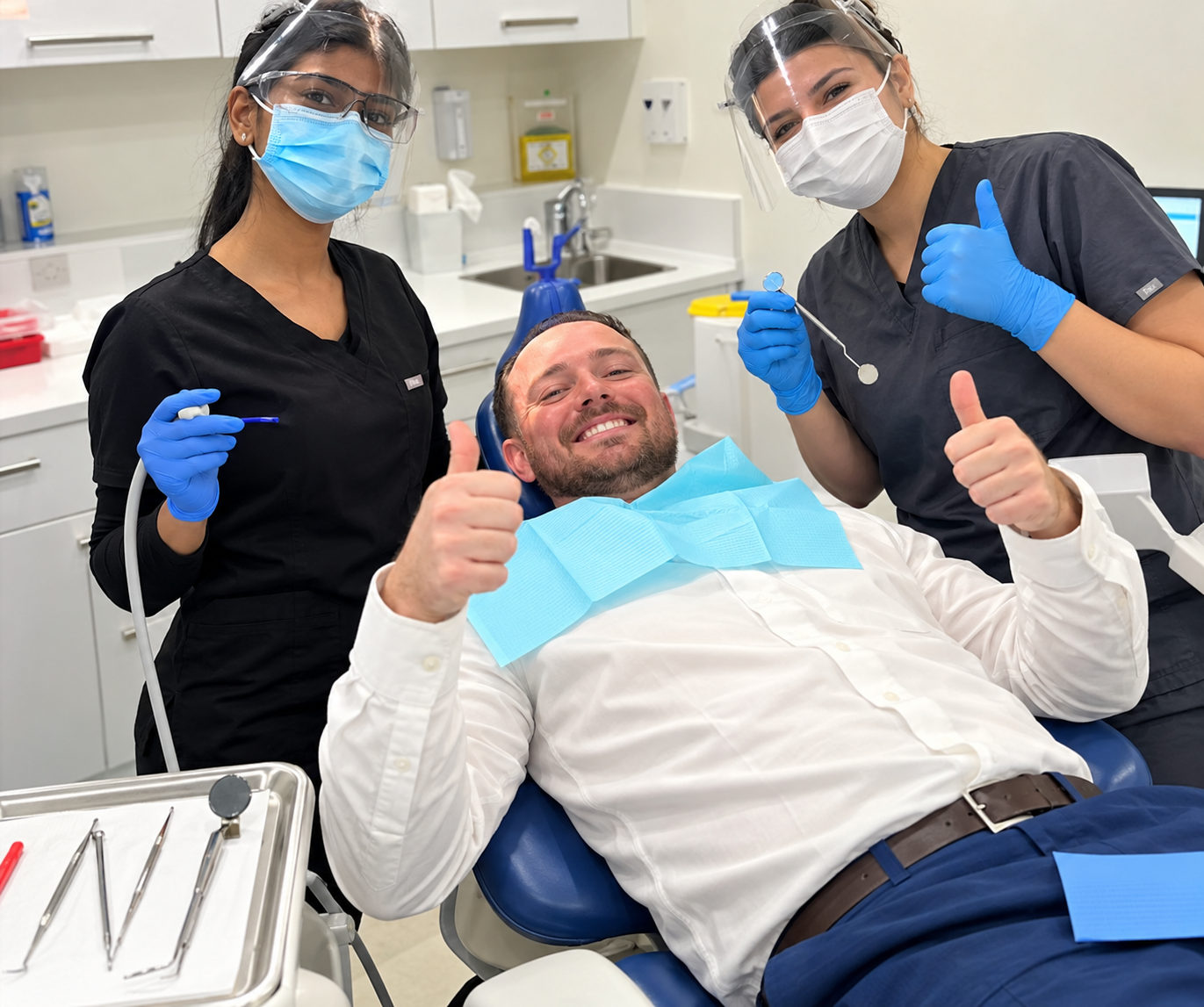 Smiling patient giving a thumbs up with the Smile Perfections team.